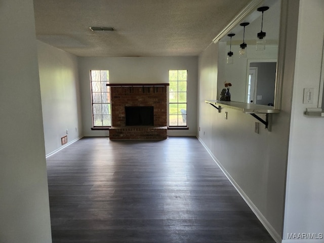 unfurnished living room with a fireplace, baseboards, dark wood-type flooring, and a textured ceiling