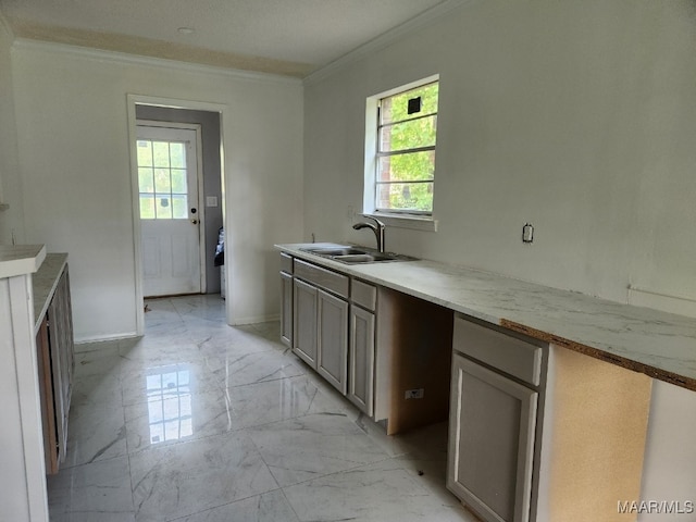 kitchen featuring marble finish floor, baseboards, ornamental molding, and a sink