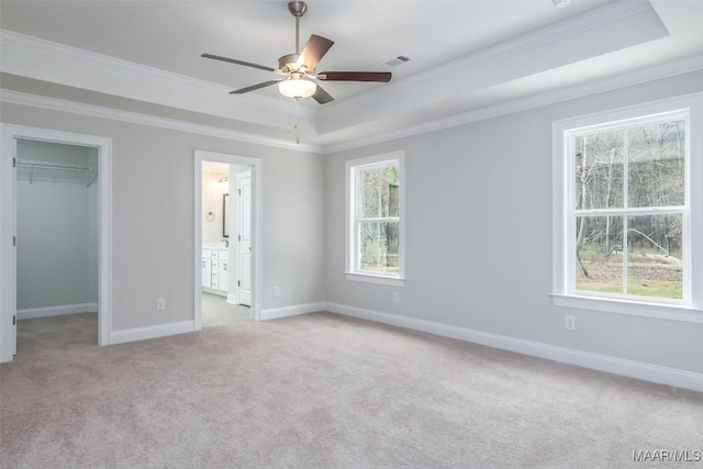 unfurnished bedroom featuring light carpet, baseboards, visible vents, a raised ceiling, and a spacious closet