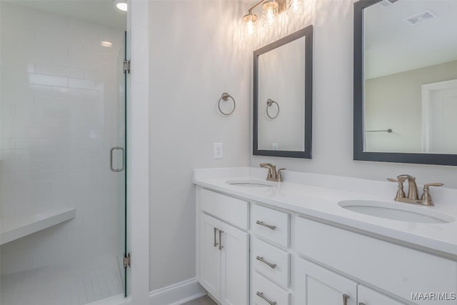 bathroom featuring double vanity, a stall shower, visible vents, and a sink