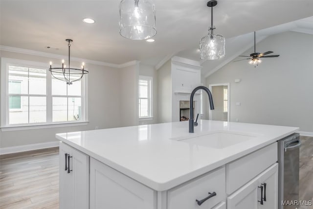 kitchen featuring a fireplace, a center island with sink, light countertops, white cabinetry, and a sink