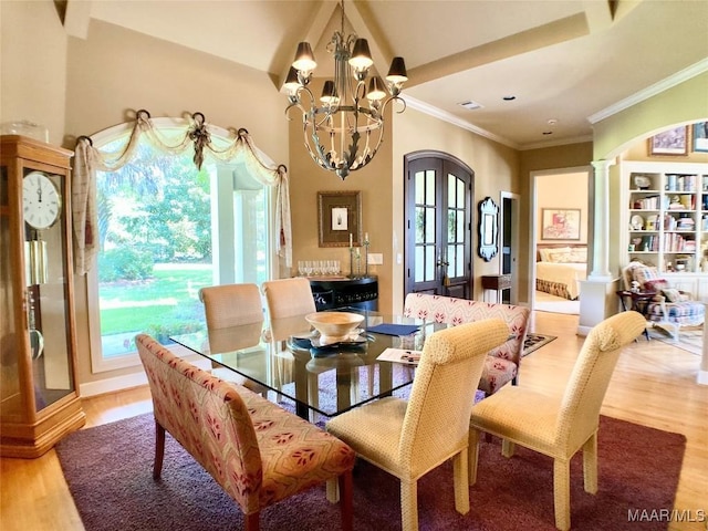 dining space with ornate columns, an inviting chandelier, ornamental molding, light wood-style floors, and visible vents