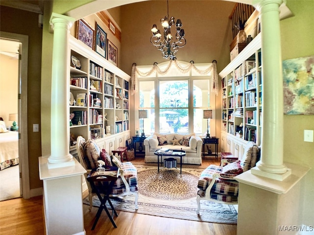 living area with decorative columns, hardwood / wood-style floors, and a chandelier