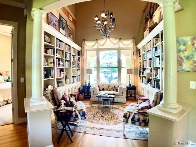 living area with decorative columns, arched walkways, a high ceiling, and wood finished floors