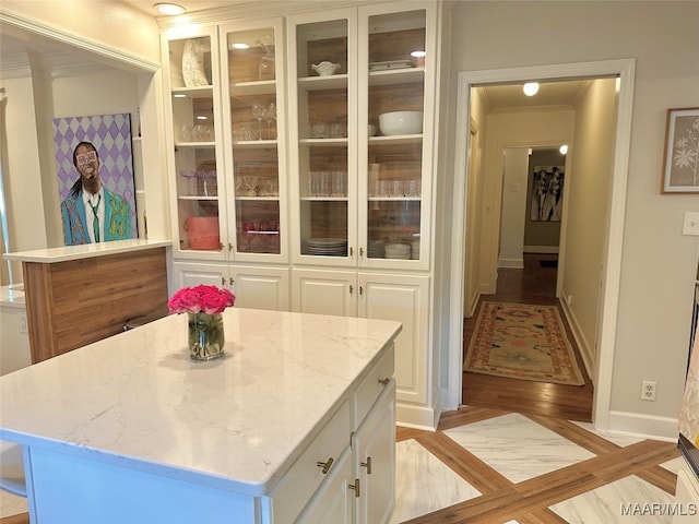 kitchen featuring crown molding, light hardwood / wood-style flooring, white cabinetry, and a kitchen island