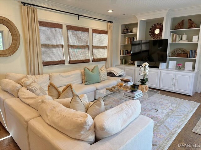 living room with built in shelves, hardwood / wood-style flooring, and crown molding