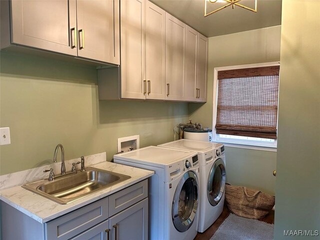 clothes washing area featuring washing machine and clothes dryer, cabinets, and sink