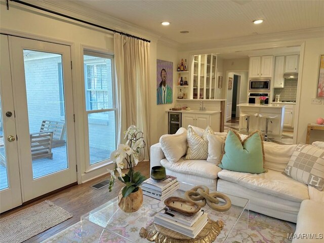 living room with sink, a healthy amount of sunlight, beverage cooler, and light hardwood / wood-style floors