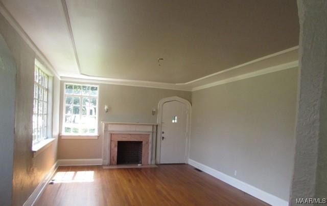 unfurnished living room with a fireplace, ornamental molding, and hardwood / wood-style floors