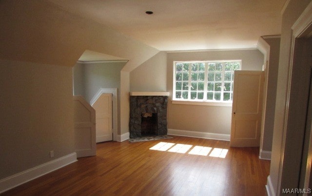 additional living space with wood-type flooring, a fireplace, and lofted ceiling