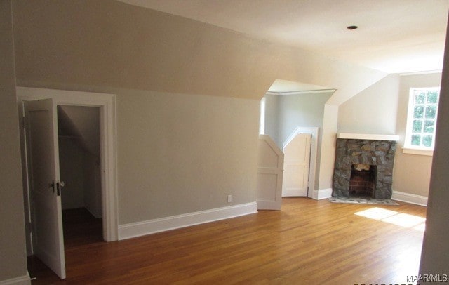 unfurnished living room with a fireplace, hardwood / wood-style flooring, and vaulted ceiling