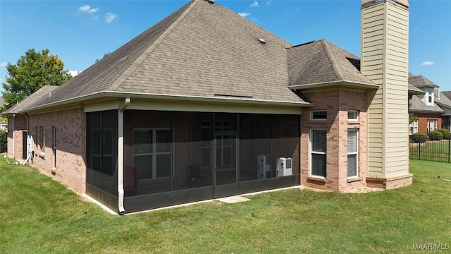 rear view of house with a sunroom and a yard