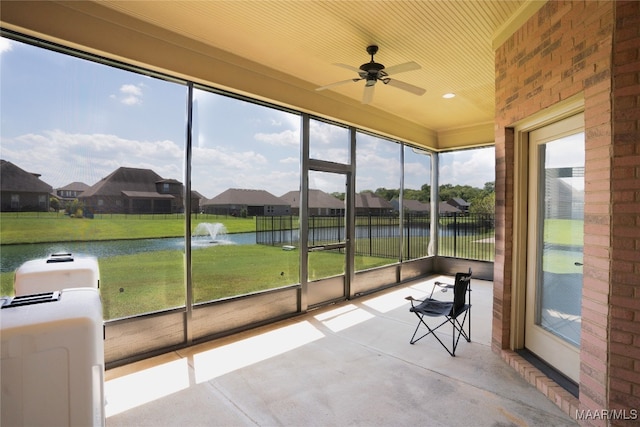 unfurnished sunroom featuring a wealth of natural light, a water view, and ceiling fan