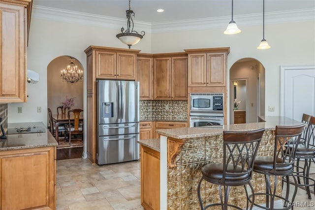 kitchen featuring ornamental molding, appliances with stainless steel finishes, light stone countertops, hanging light fixtures, and a kitchen breakfast bar