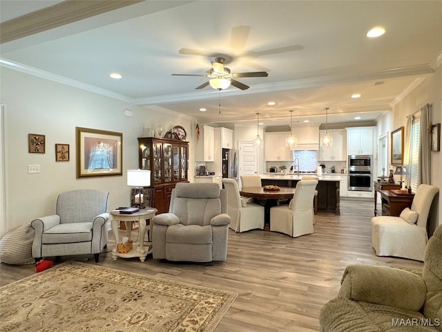 living room with ceiling fan, light hardwood / wood-style flooring, crown molding, and sink