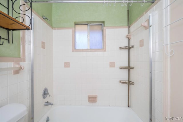 bathroom with tiled shower / bath combo and toilet