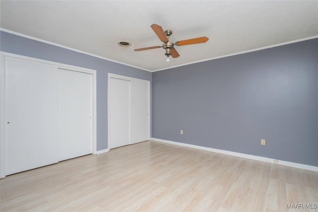 unfurnished bedroom with ceiling fan, ornamental molding, two closets, and light wood-type flooring