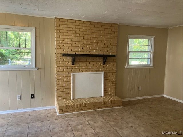 unfurnished living room featuring tile patterned flooring, a brick fireplace, wooden walls, and brick wall