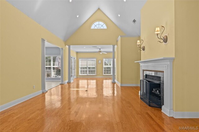 unfurnished living room featuring a fireplace, ceiling fan, high vaulted ceiling, and light wood-type flooring