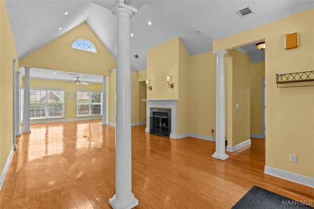 unfurnished living room featuring ceiling fan, decorative columns, light hardwood / wood-style floors, and a premium fireplace