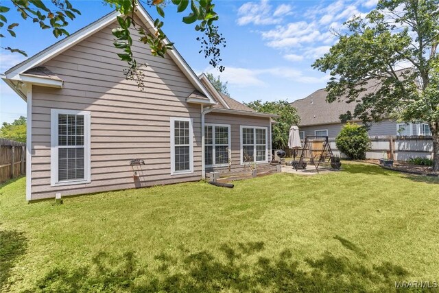 back of house with a lawn and a patio