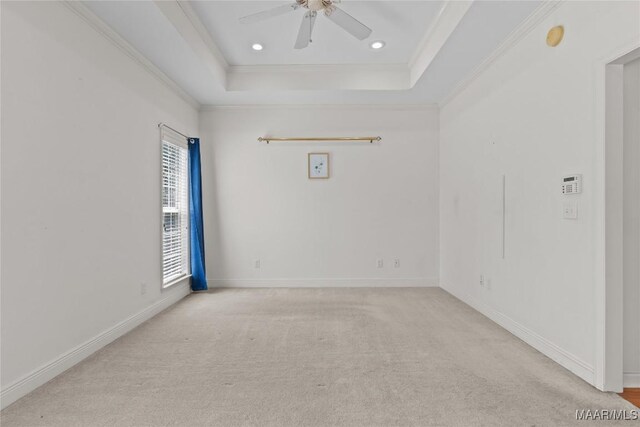 carpeted empty room featuring ceiling fan, crown molding, and a tray ceiling