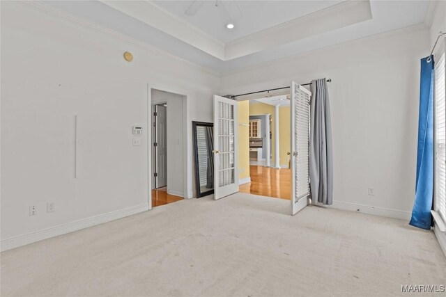 unfurnished bedroom with a tray ceiling, carpet floors, ceiling fan, and ornamental molding