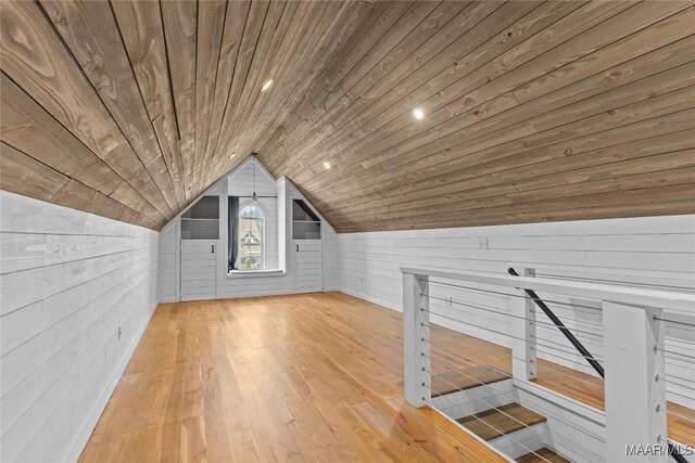 additional living space with wood ceiling, light hardwood / wood-style flooring, wooden walls, and lofted ceiling