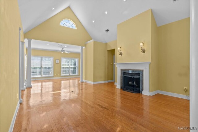 unfurnished living room featuring high vaulted ceiling, a fireplace, light hardwood / wood-style flooring, and ceiling fan