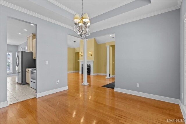 spare room with a tray ceiling, ornamental molding, light tile patterned floors, and an inviting chandelier