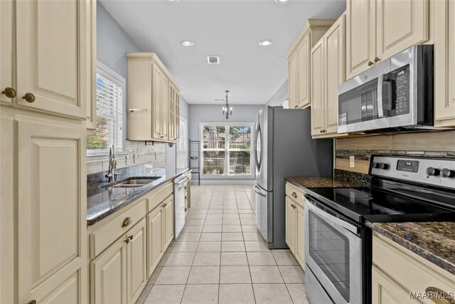 kitchen with sink, decorative light fixtures, cream cabinetry, and stainless steel appliances