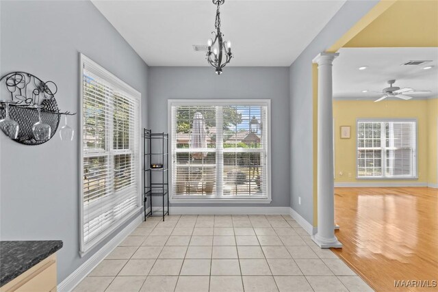 unfurnished dining area featuring light hardwood / wood-style flooring, ceiling fan with notable chandelier, and decorative columns