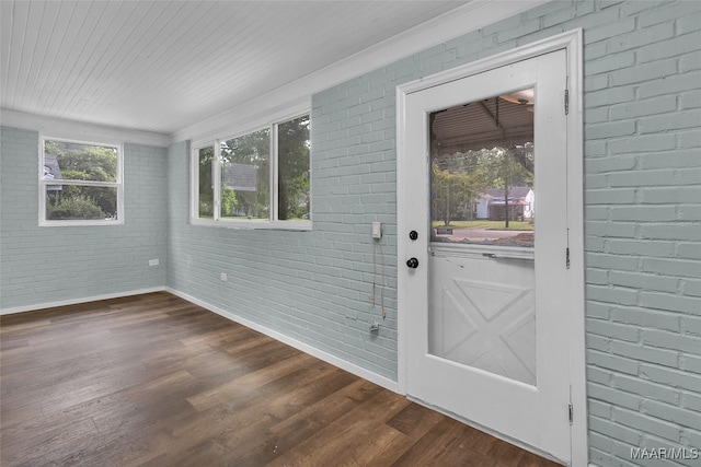 doorway with brick wall and hardwood / wood-style flooring