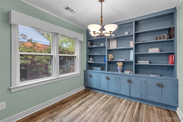 home office with crown molding, hardwood / wood-style floors, and an inviting chandelier