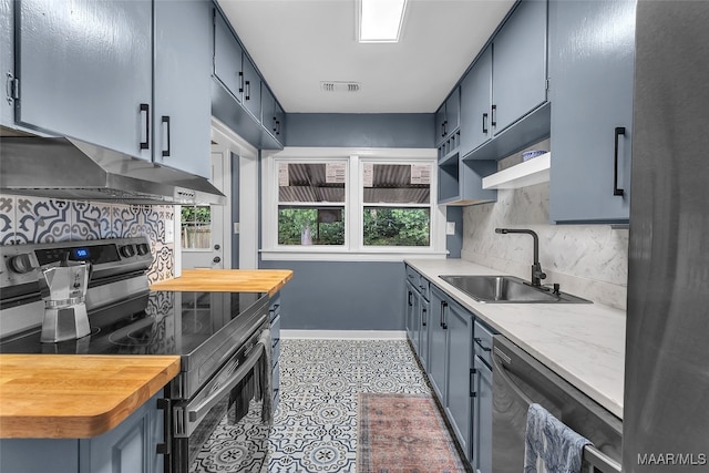 kitchen with backsplash, wall chimney exhaust hood, appliances with stainless steel finishes, light tile patterned floors, and sink