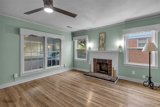 unfurnished living room featuring ceiling fan, plenty of natural light, light hardwood / wood-style floors, and a brick fireplace