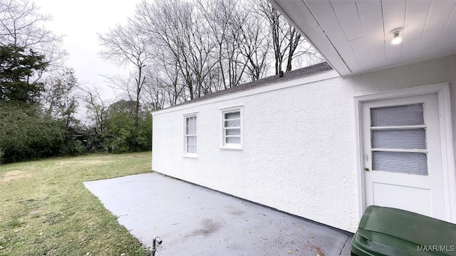 view of property exterior with a patio area, a lawn, and stucco siding