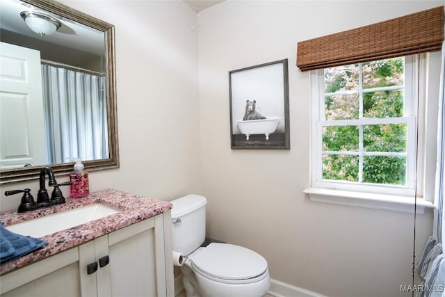 bathroom with toilet, vanity, and a healthy amount of sunlight