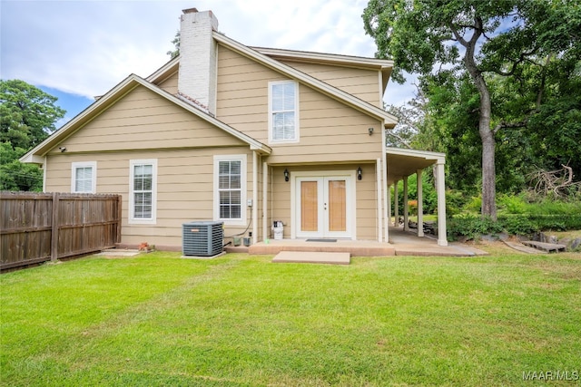 rear view of property featuring central air condition unit and a yard