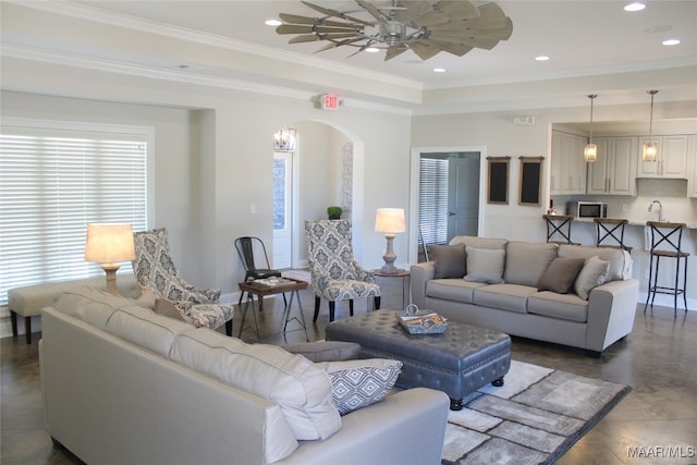 living area featuring ceiling fan, ornamental molding, arched walkways, and recessed lighting