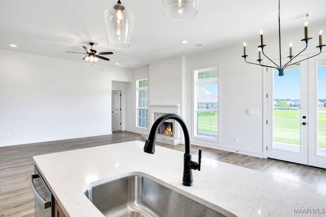 1415 Barret Park Way, Montgomery, AL 36117 - kitchen featuring a sink, a chandelier, a warm lit fireplace, light wood-style flooring, and dishwasher
