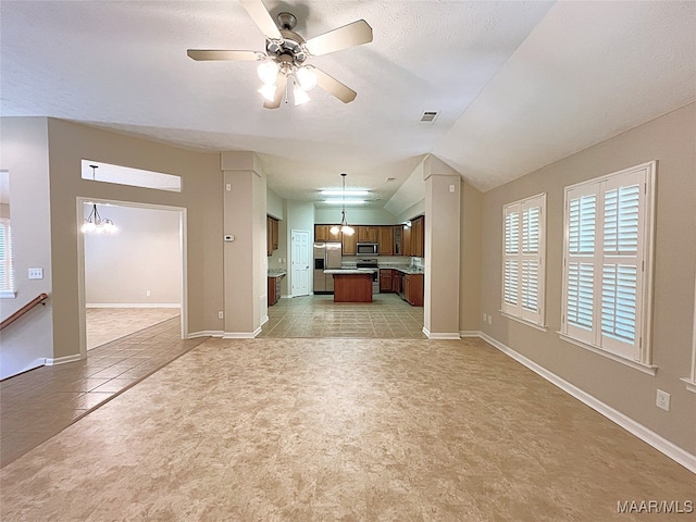 unfurnished living room with ceiling fan with notable chandelier, lofted ceiling, and light tile patterned floors