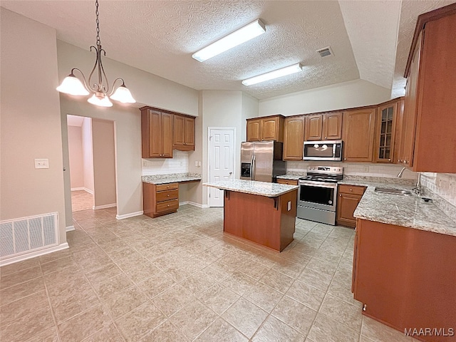 kitchen with appliances with stainless steel finishes, a textured ceiling, sink, a chandelier, and a center island