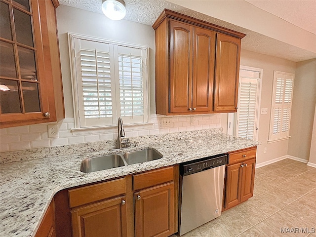 kitchen with dishwasher, light stone countertops, sink, and tasteful backsplash