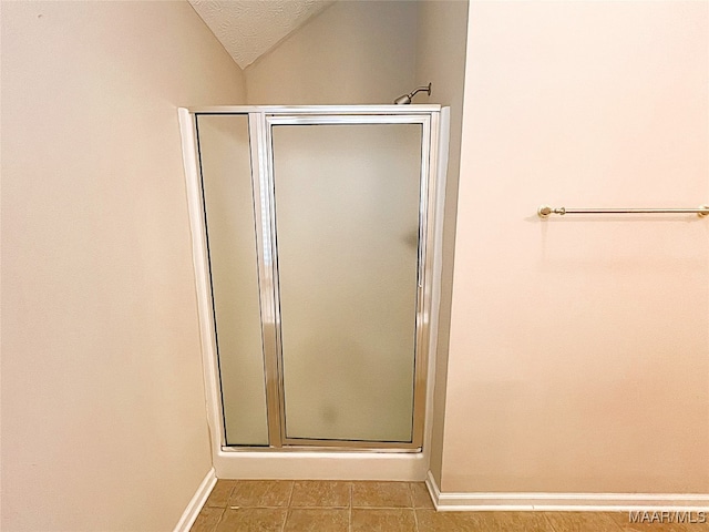 bathroom featuring vaulted ceiling, a shower with door, and a textured ceiling