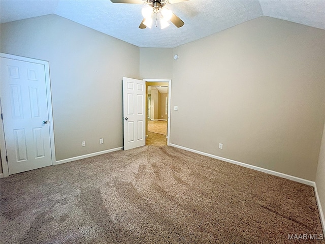 unfurnished bedroom featuring carpet, ceiling fan, a textured ceiling, and vaulted ceiling