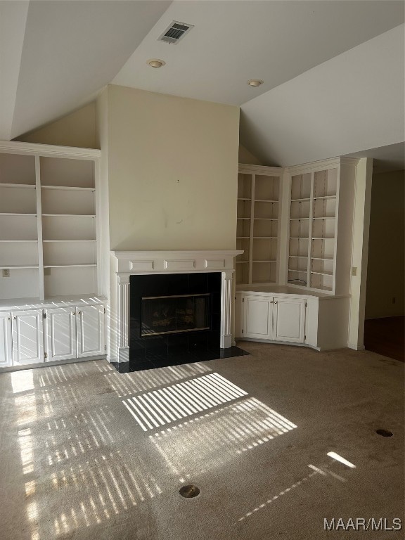 unfurnished living room with lofted ceiling, carpet, built in shelves, and a tile fireplace