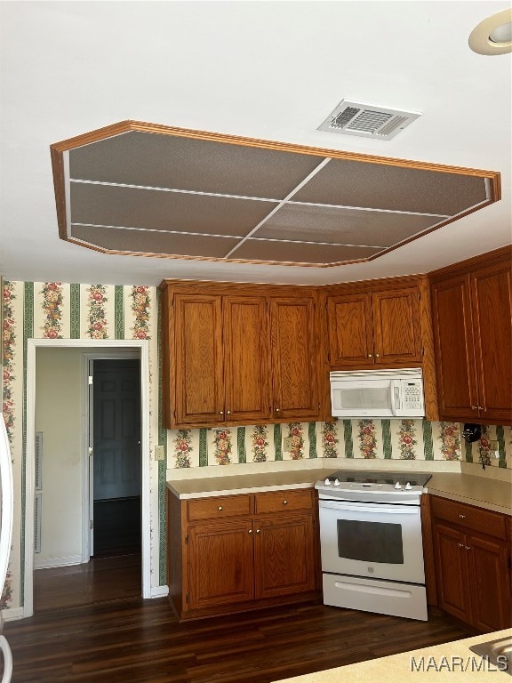 kitchen with white appliances and dark hardwood / wood-style flooring