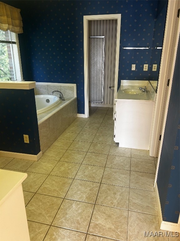 bathroom featuring tiled tub, vanity, and tile patterned floors