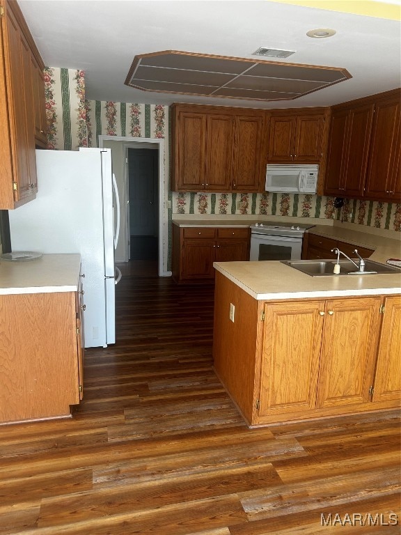 kitchen with white appliances, kitchen peninsula, sink, and dark hardwood / wood-style floors